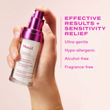 Hand holding a Murad skincare serum with product details on a pink background